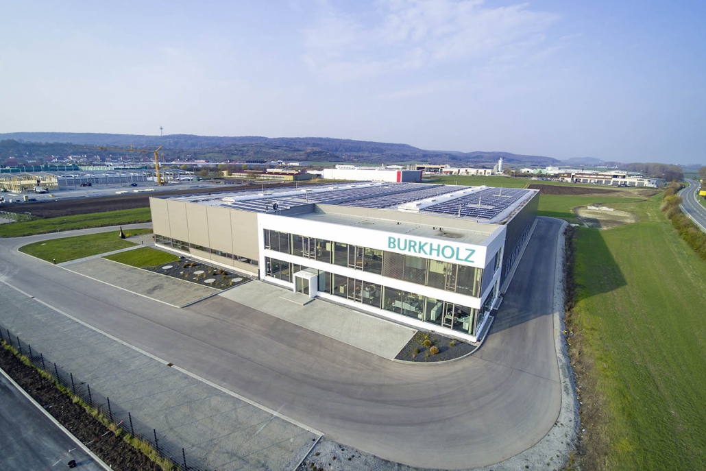 Gerhäuser Bau - Moderne Gewerbebau-Anlage in Mittelfranken mit Solarpanelen auf dem Dach und Burkholz-Beschriftung, professionelle Baufirma für Massivbau.