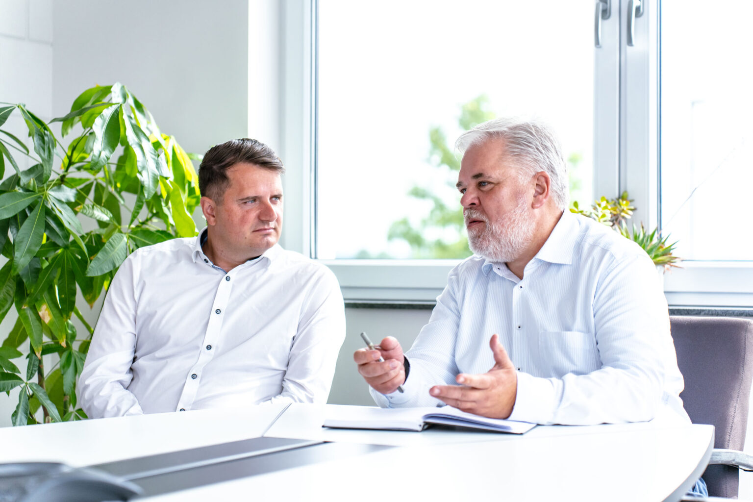 Zwei Geschäftsmänner besprechen Bauprojekte bei Gerhäuser Bau, spezialisiert auf Massivbau und Hausbau in Mittelfranken.