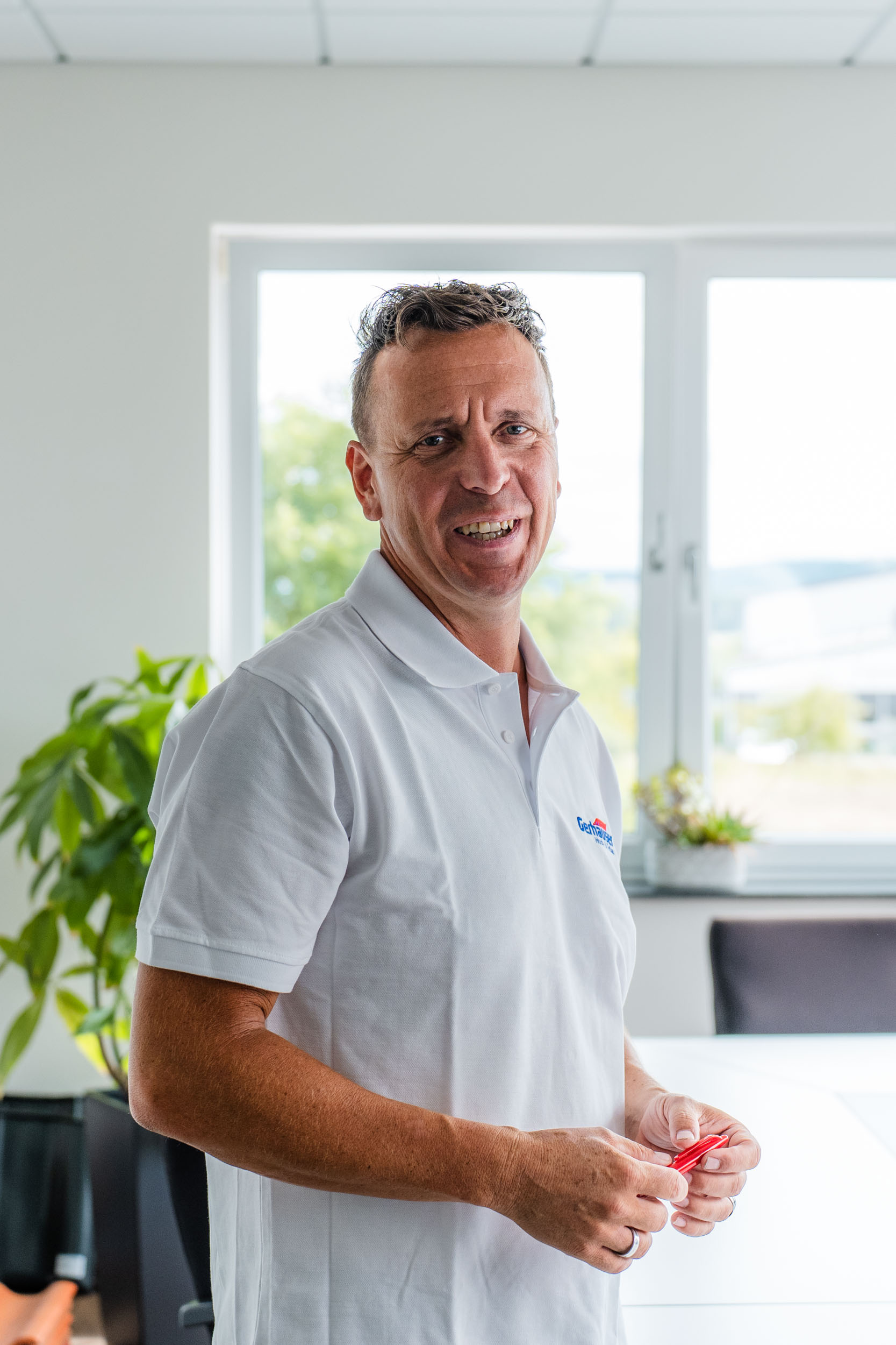 Mitarbeiter der Gerhäuser Bau, Baufirma für Massivbau und Hausbau in Mittelfranken, präsentiert sich im modernen Büro mit Blick ins Grüne.