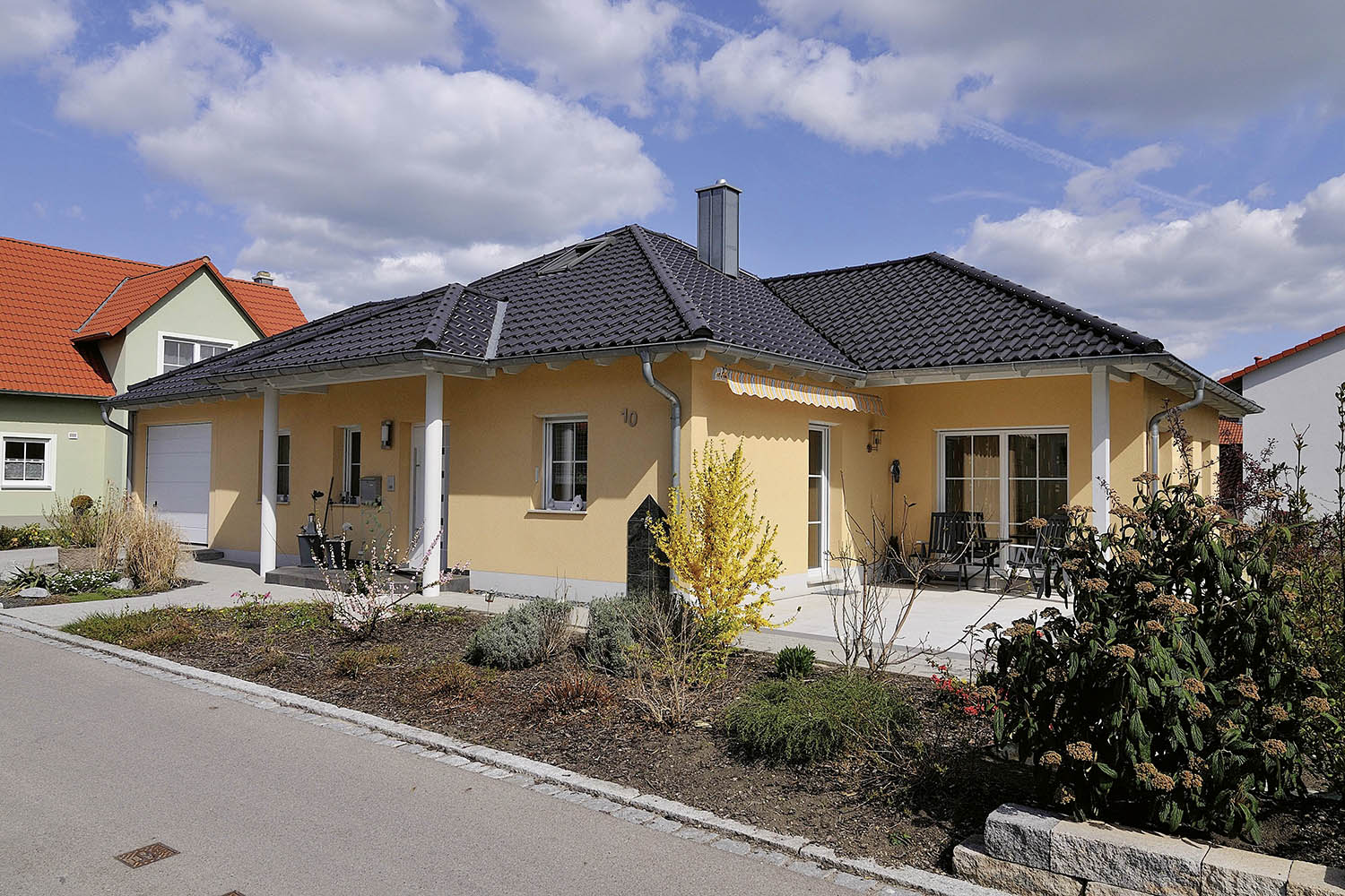 Modernes Einfamilienhaus mit gelblicher Fassade und dunklem Dach von Gerhäuser Bau - Massivbau Spezialist für Hausbau in Mittelfranken und Franken.
