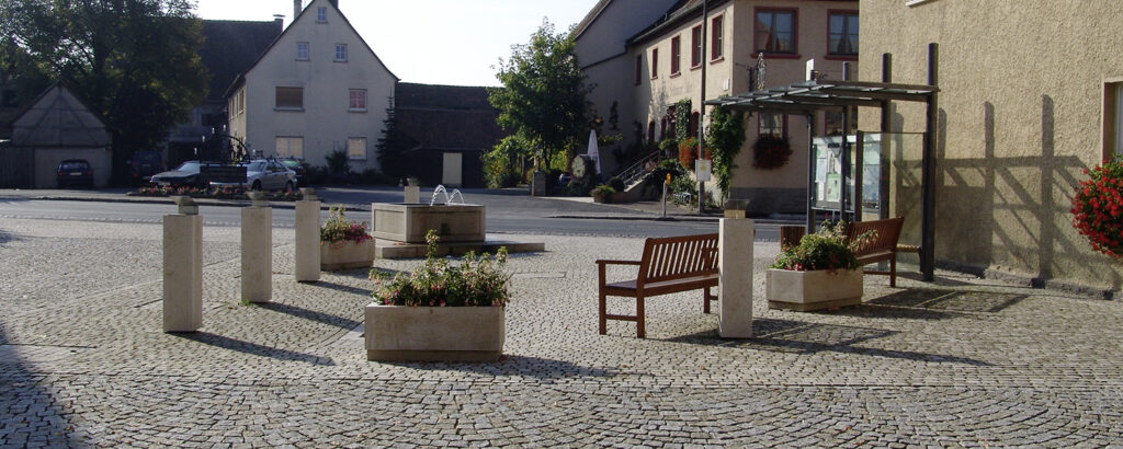 Gerhäuser Bau - Baufirma für Massivbau in Mittelfranken. Moderner Dorfplatz mit Sitzbereichen und Grünanlagen, gestaltet durch professionelle Hausbau-Expertise.
