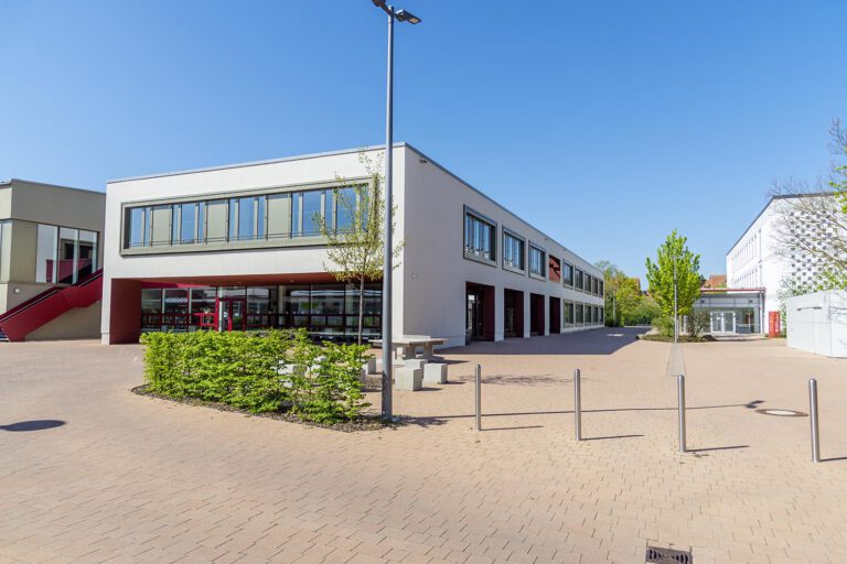Modernes Gewerbebau-Projekt von Gerhäuser Bau in Mittelfranken mit weißer Fassade, roten Akzenten und großzügigen Glasflächen. Gymnasium Bad Windsheim