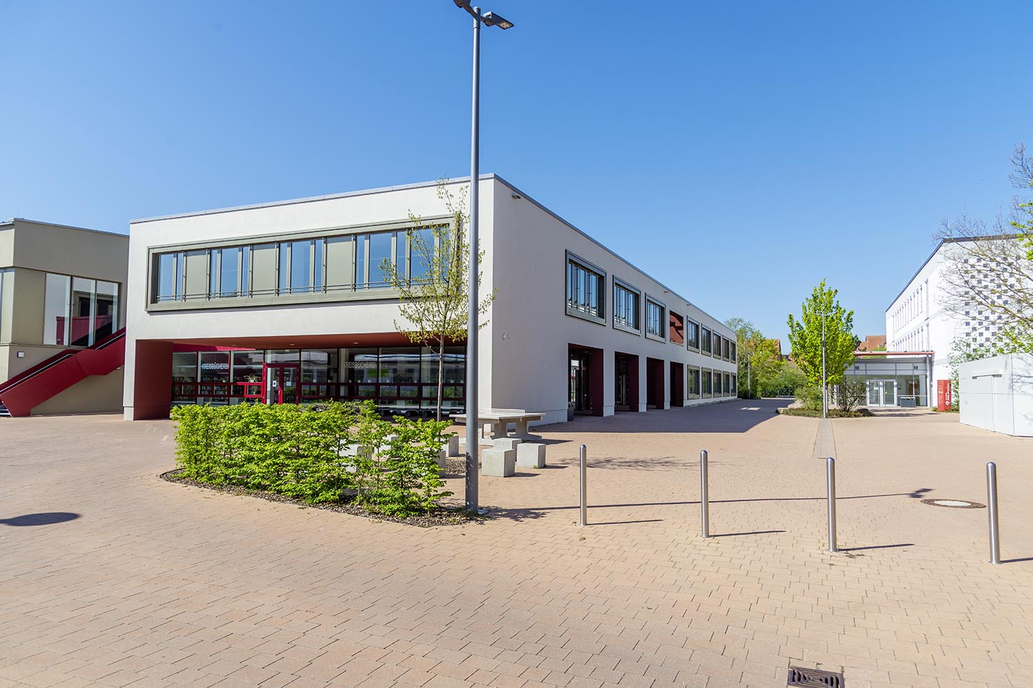 Modernes Gewerbebau-Projekt von Gerhäuser Bau in Mittelfranken mit weißer Fassade, roten Akzenten und großzügigen Glasflächen. Gymnasium Bad Windsheim