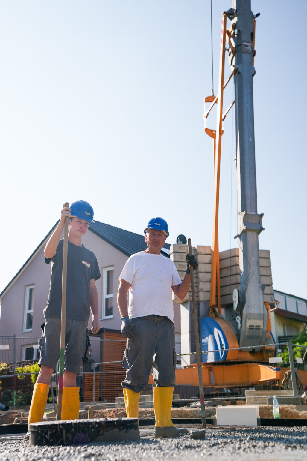Zwei Bauarbeiter der Gerhäuser Bau Baufirma beim Massivbau in Mittelfranken mit Baumaschinen und Wohnhaus im Hintergrund