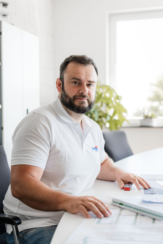 Mitarbeiter der Gerhäuser Bau am Schreibtisch mit Bauplänen. Massivbau Spezialist in Mittelfranken für professionellen Hausbau.